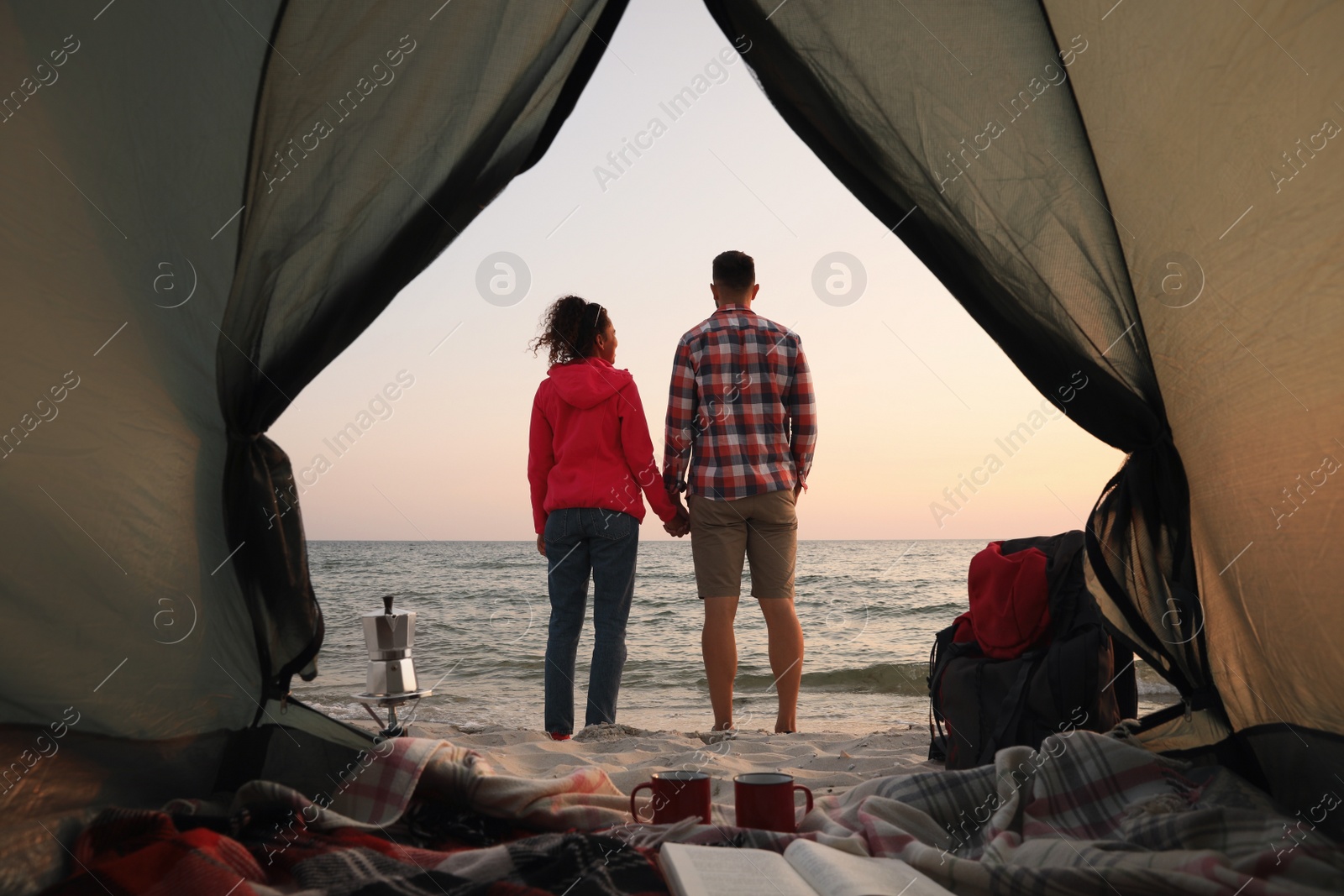 Photo of Couple near sea at sunset, view from camping tent