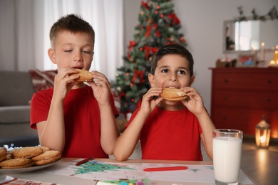 Photo of Little children eating cookies at home. Christmas celebration