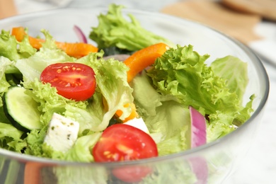 Photo of Bowl of tasty fresh Greek salad on table, closeup