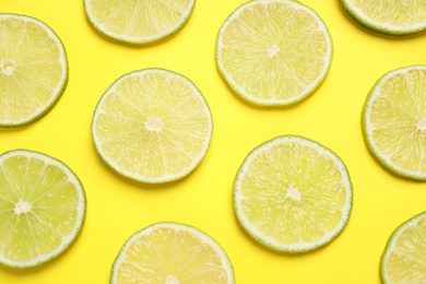 Fresh juicy lime slices on yellow background, flat lay