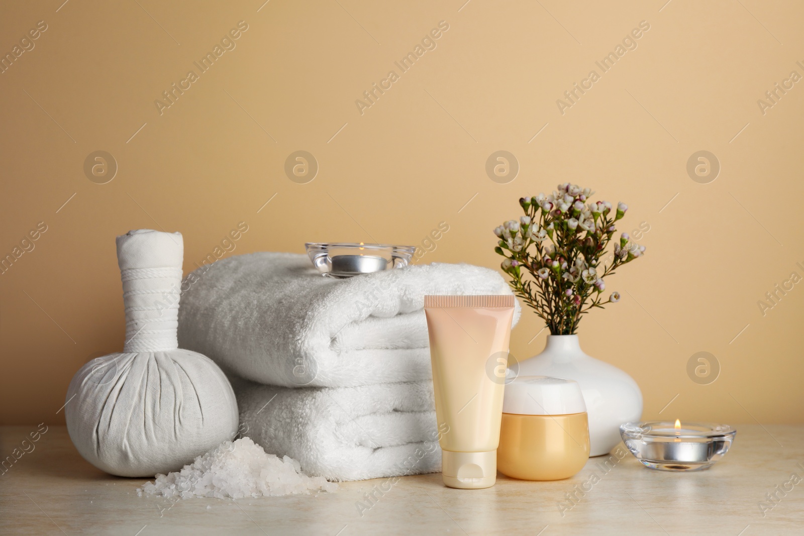 Photo of Composition with different spa products, candles and flowers on beige table