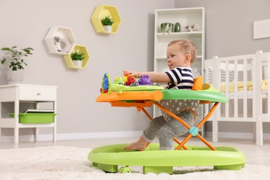 Cute baby making first steps with toy walker at home, space for text