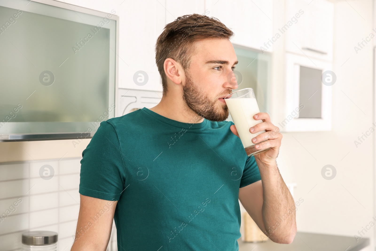 Photo of Young man drinking tasty milk at home