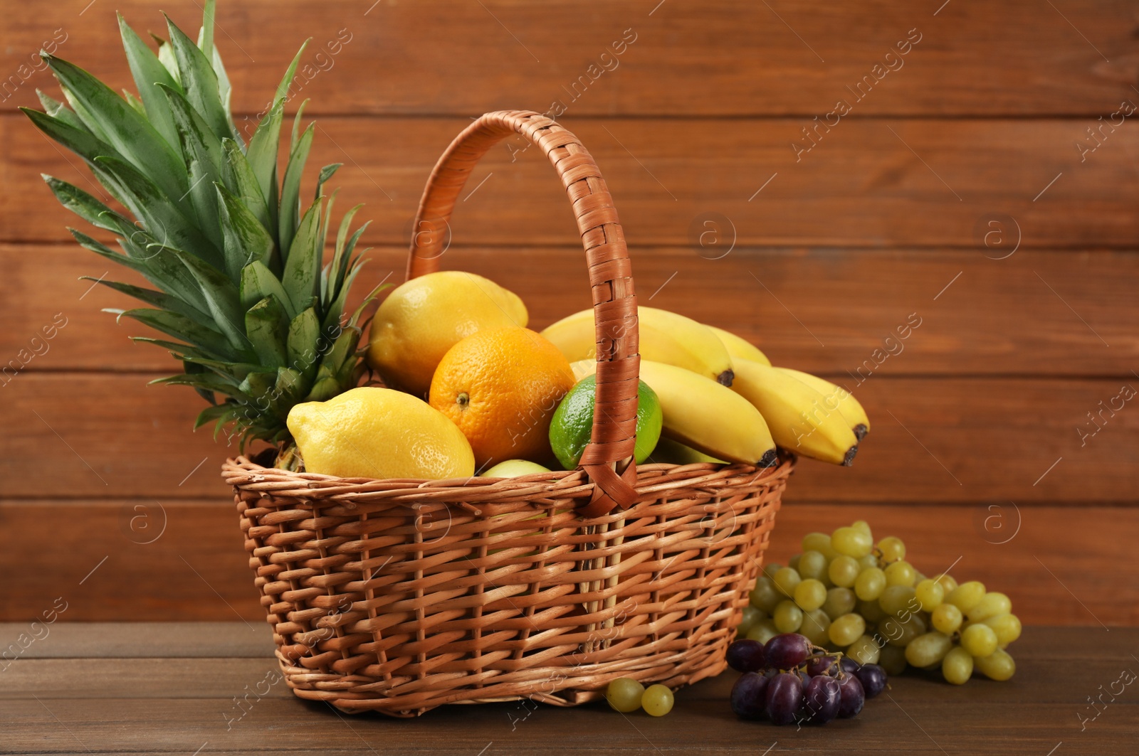 Photo of Wicker basket with different ripe fruits on wooden table