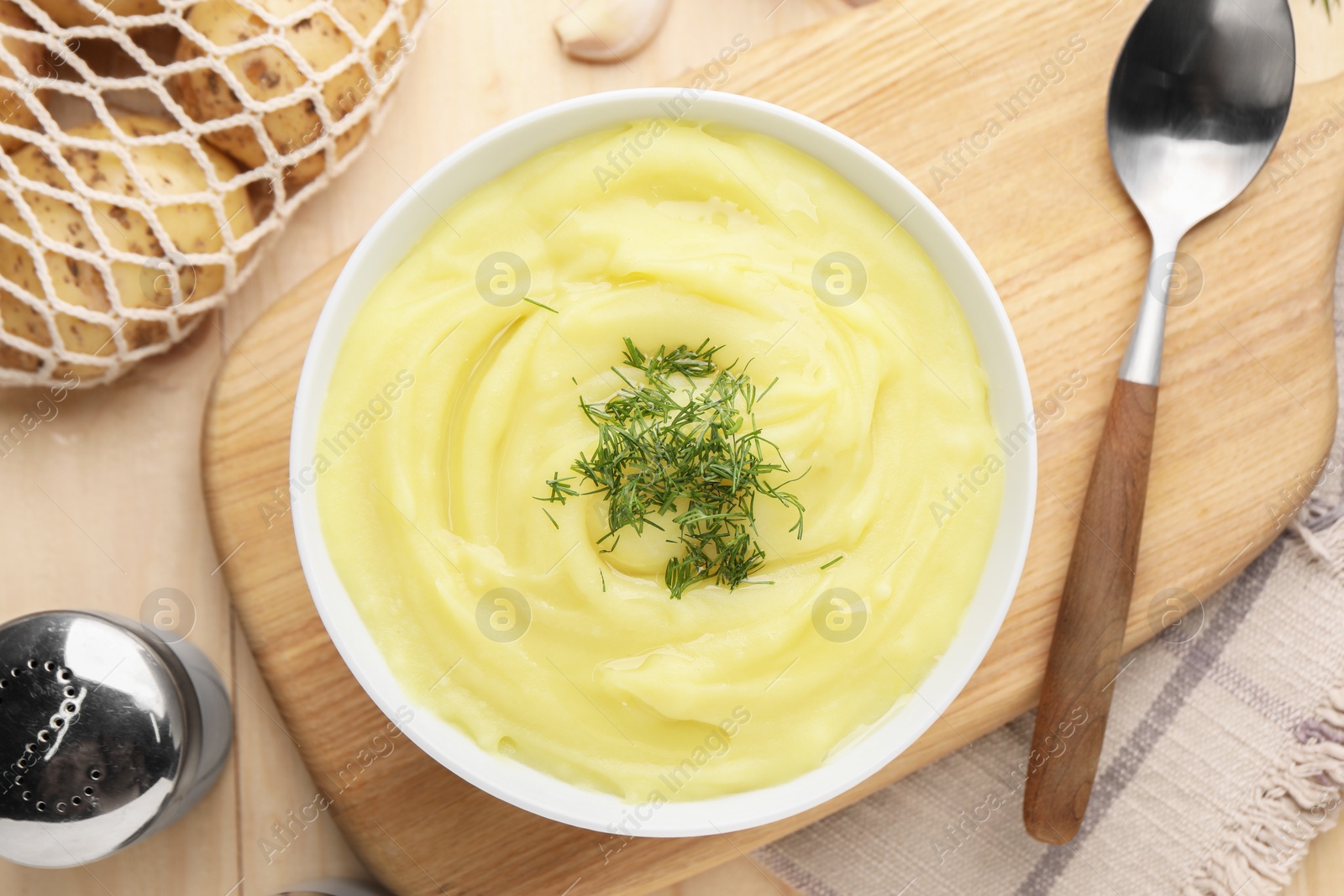 Photo of Bowl of tasty cream soup with dill and spoon on wooden table, flat lay