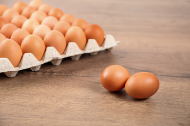 Photo of Raw brown chicken eggs on wooden table