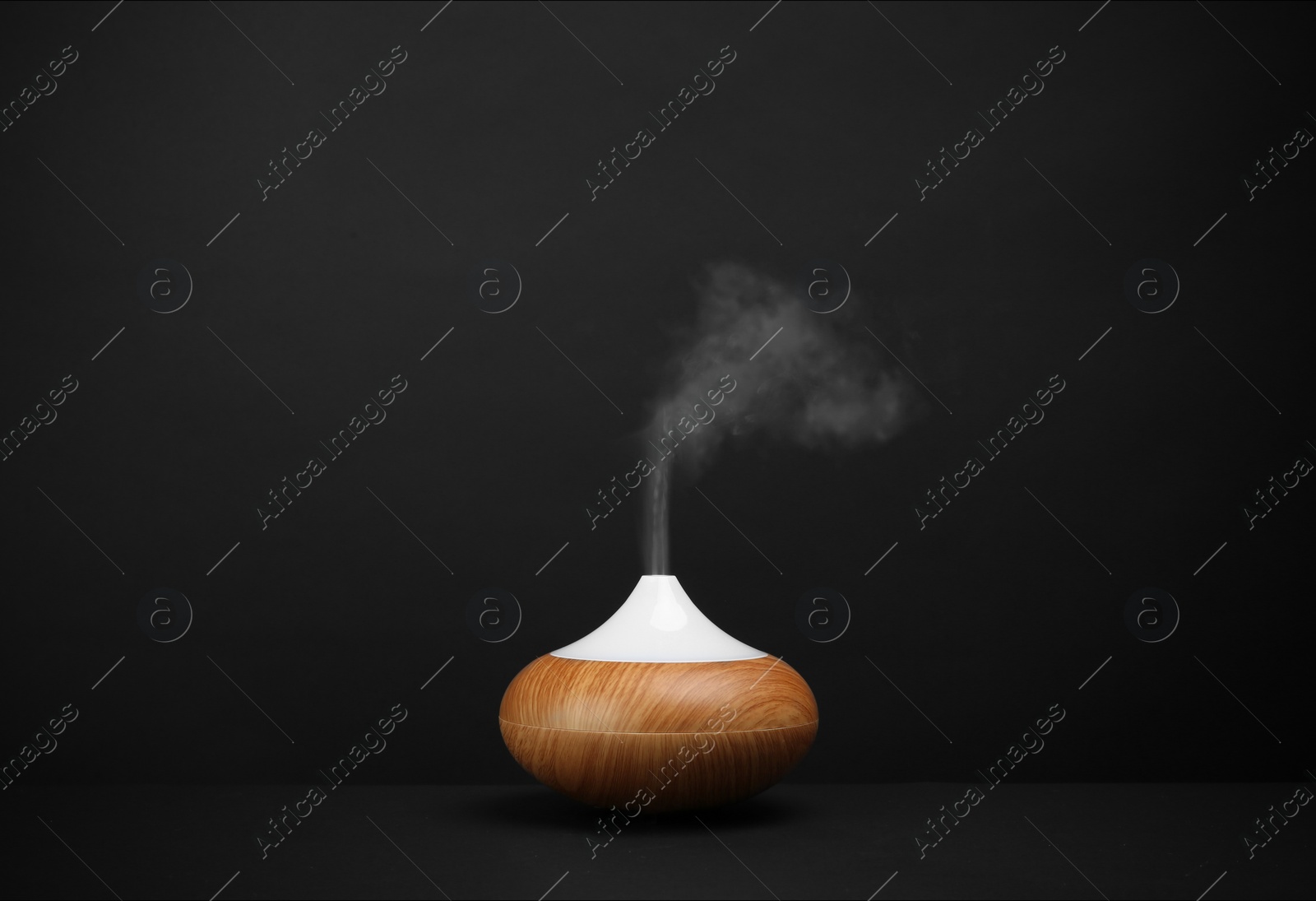 Photo of Modern essential oil diffuser on black background. Space for text