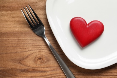 Photo of Plate with red heart, fork and space for text on wooden table, flat lay. Healthy diet concept