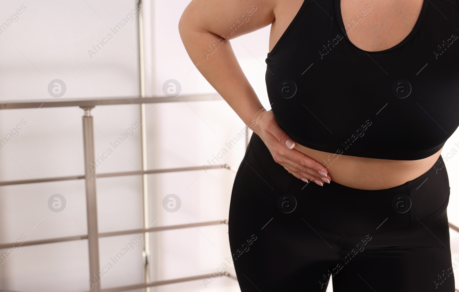 Photo of Overweight woman suffering from pain in right side on stairs indoors, closeup. Space for text