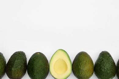 Photo of Tasty whole and cut avocados on white background, flat lay. Space for text