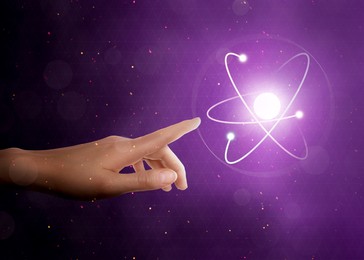Image of Woman pointing at virtual model of atom on purple background, closeup