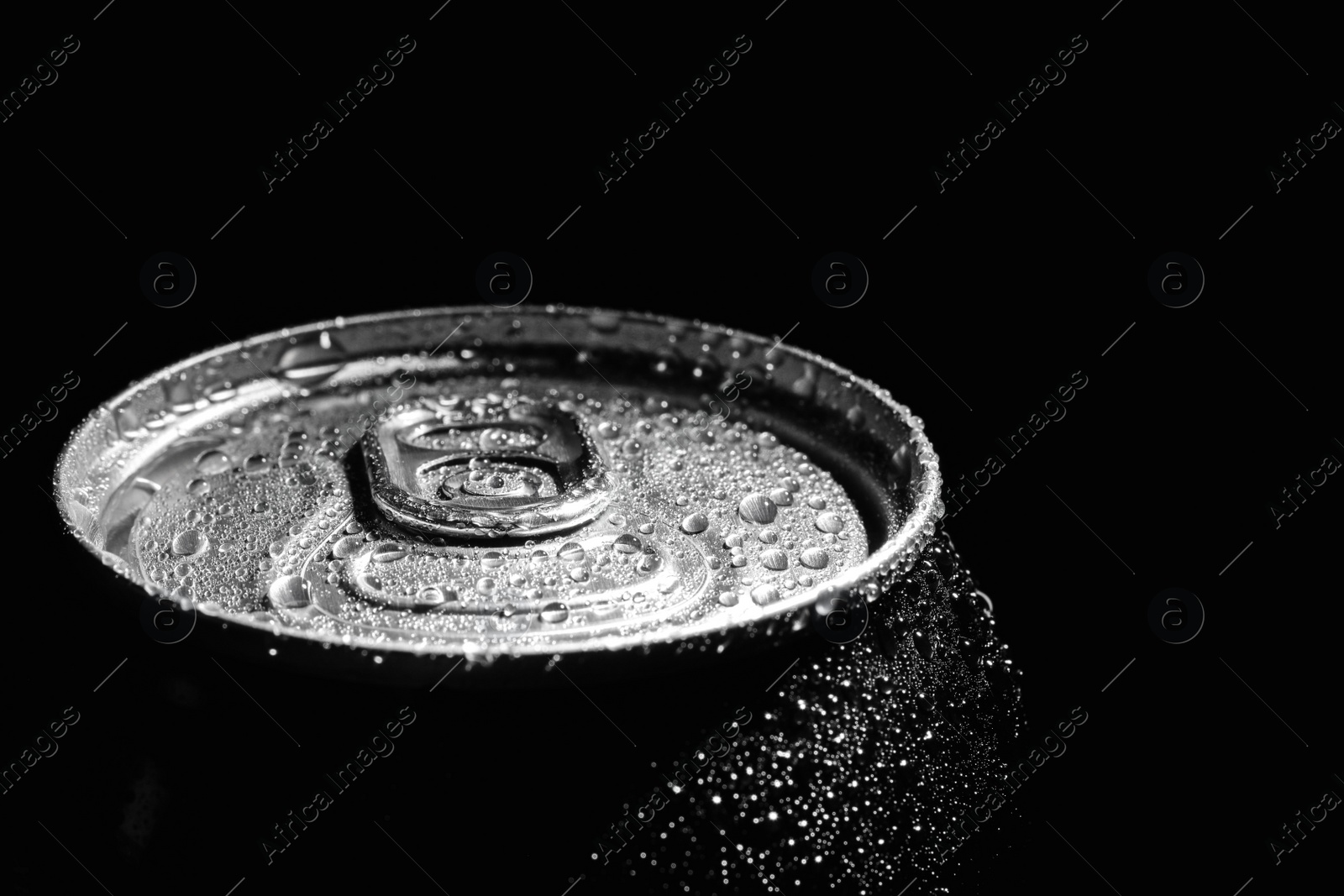 Photo of Aluminum can of beverage covered with water drops on black background, closeup