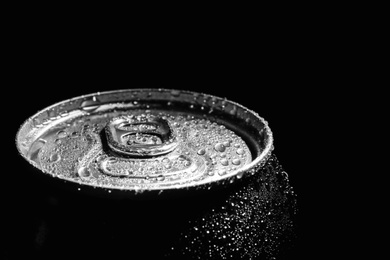 Photo of Aluminum can of beverage covered with water drops on black background, closeup