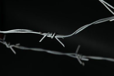 Photo of Metal barbed wire on black background, closeup