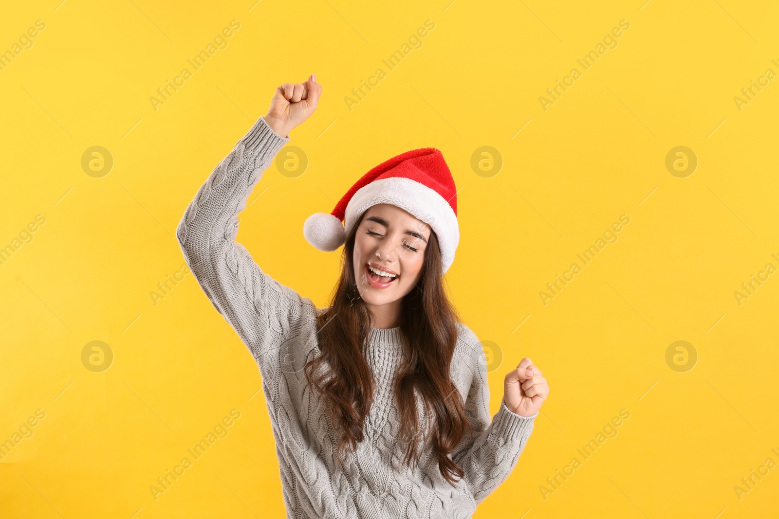 Photo of Beautiful woman wearing Santa Claus hat on yellow background