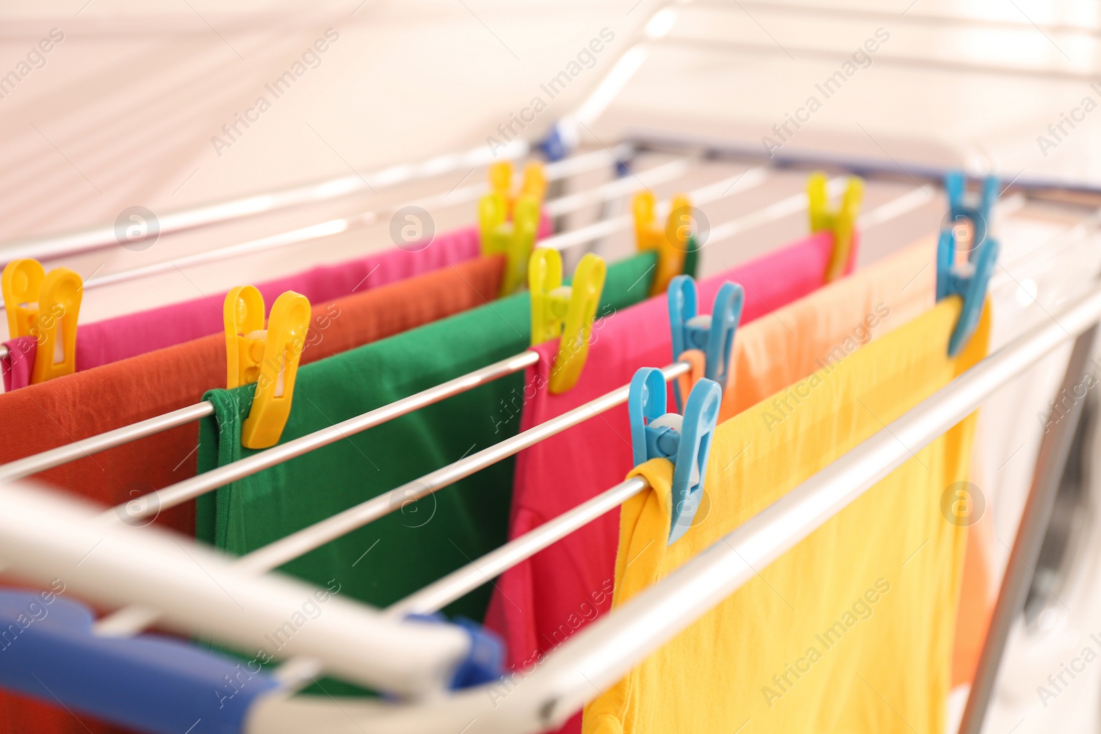 Photo of Clean laundry hanging on drying rack indoors, closeup