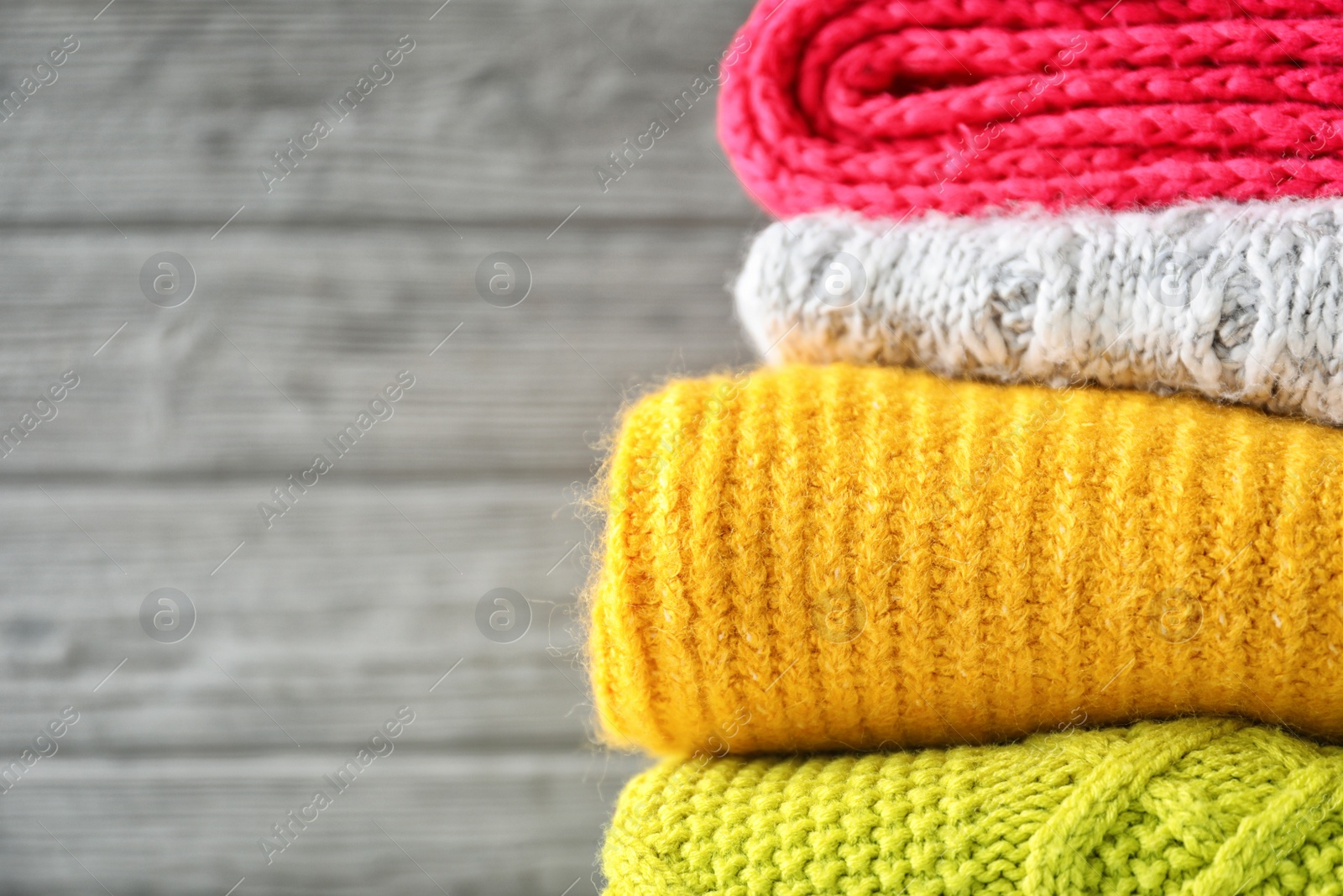 Photo of Stack of warm knitted clothes on grey background