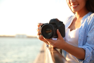 Photo of Young photographer with professional camera outdoors, closeup. Space for text