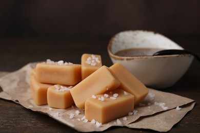 Photo of Delicious candies with sea salt and caramel sauce on wooden table, closeup