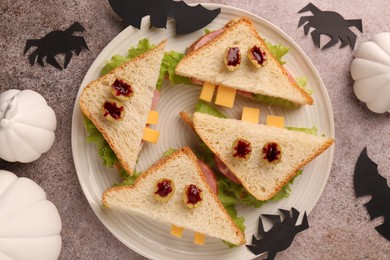 Photo of Tasty monster sandwiches and Halloween decorations on grey textured table, flat lay
