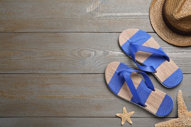 Photo of Stylish flip flops, starfish and hat on wooden background, flat lay. Space for text