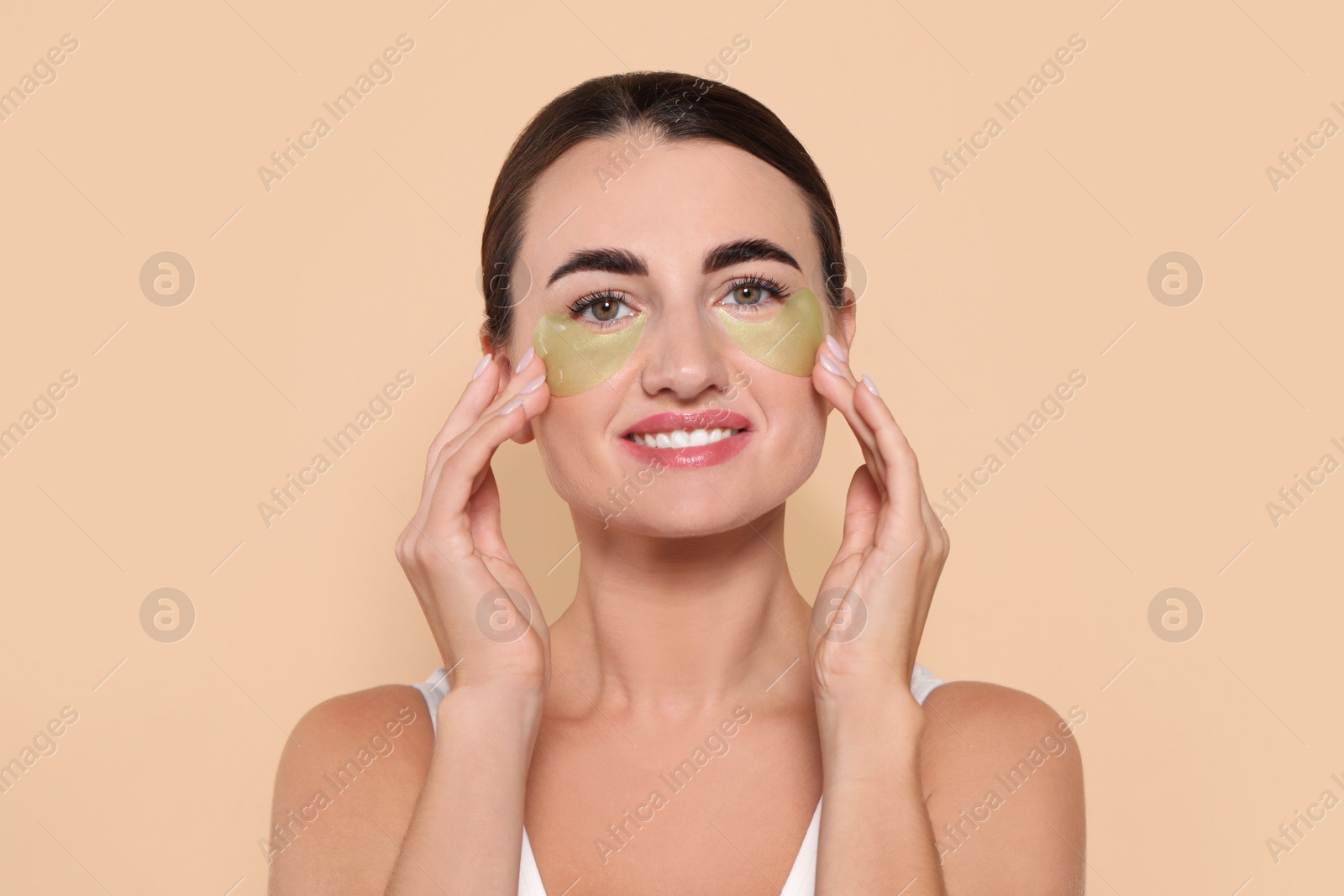 Photo of Beautiful woman with under eye patches on beige background