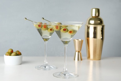 Photo of Glasses of Classic Dry Martini with olives on wooden table against grey background