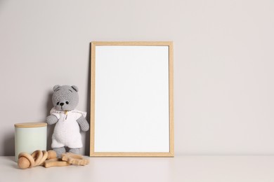 Photo of Empty square frame and different toys on white table, space for text