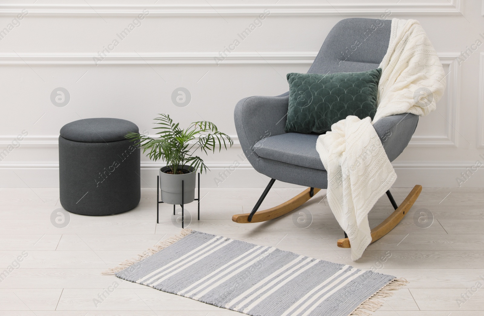 Photo of Stylish room interior with rug, plant and comfortable rocking chair