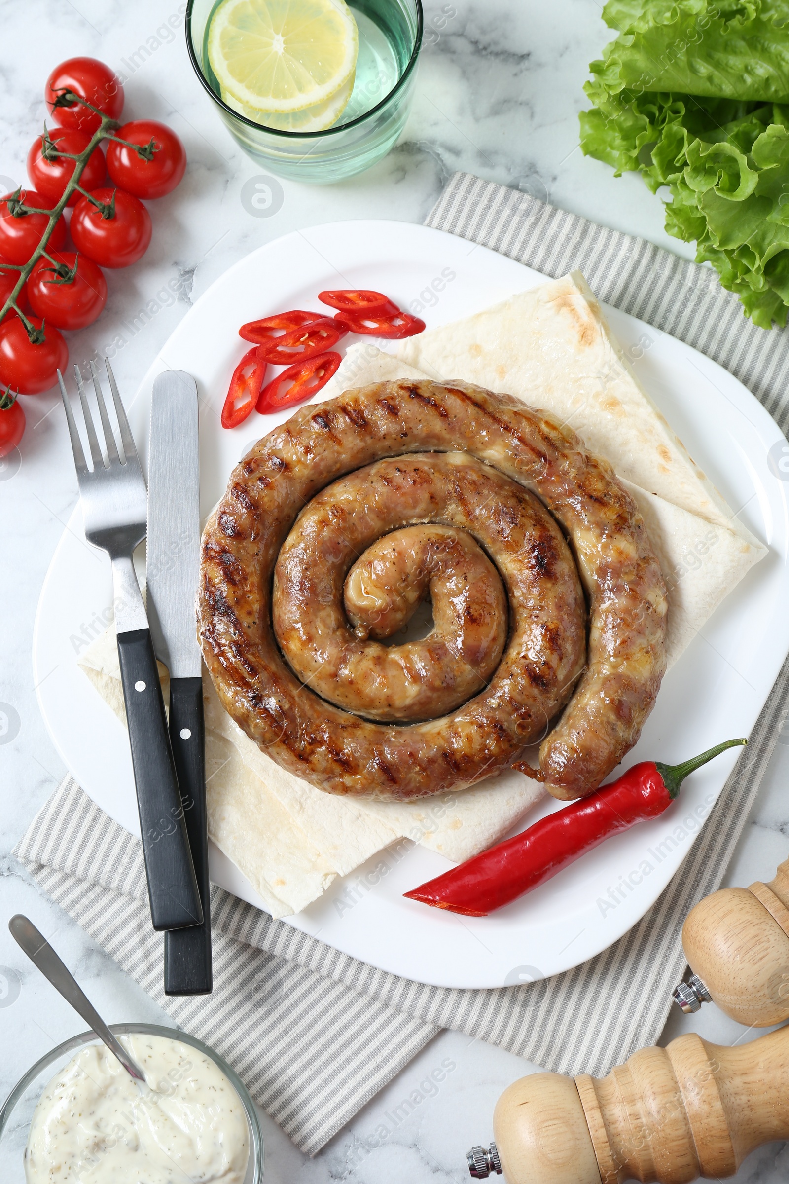 Photo of Tasty homemade sausage with chili pepper and lavash served on white marble table, flat lay