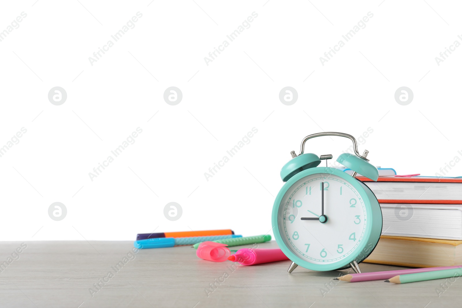 Photo of Turquoise alarm clock and different stationery on wooden table against white background, space for text. School time