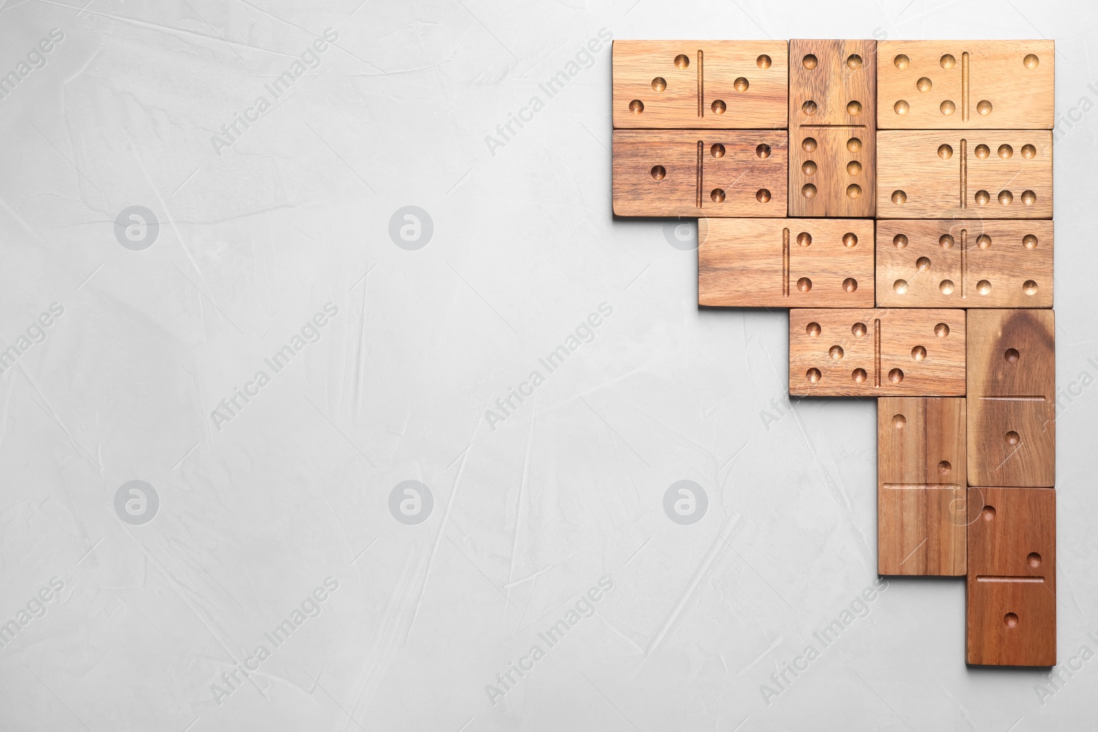 Photo of Wooden domino tiles on light grey table, flat lay. Space for text