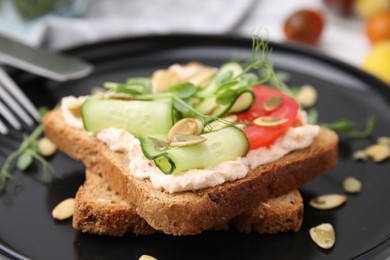 Photo of Tasty vegan sandwich with cucumber, tomato and pumpkin seeds on plate, closeup