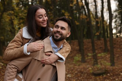 Romantic young couple spending time together in autumn park, space for text