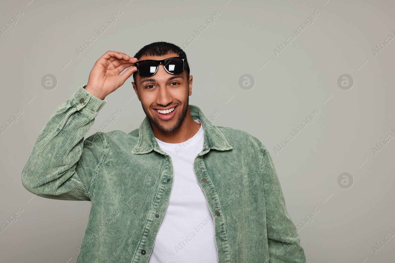 Photo of Smiling African American man wearing sunglasses on light grey background. Space for text