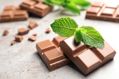 Pieces of milk chocolate with mint on gray table