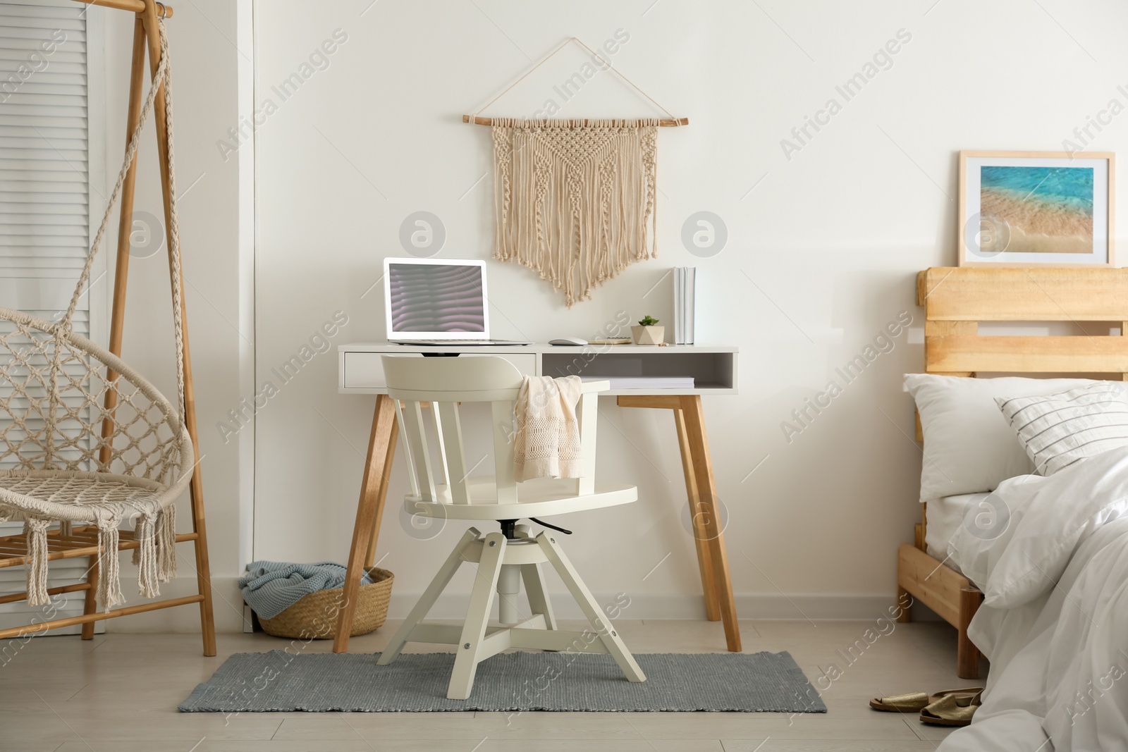 Photo of Stylish room interior with workplace, hanging chair and bed