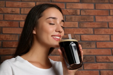 Beautiful woman with cold kvass near brick wall. Traditional Russian summer drink