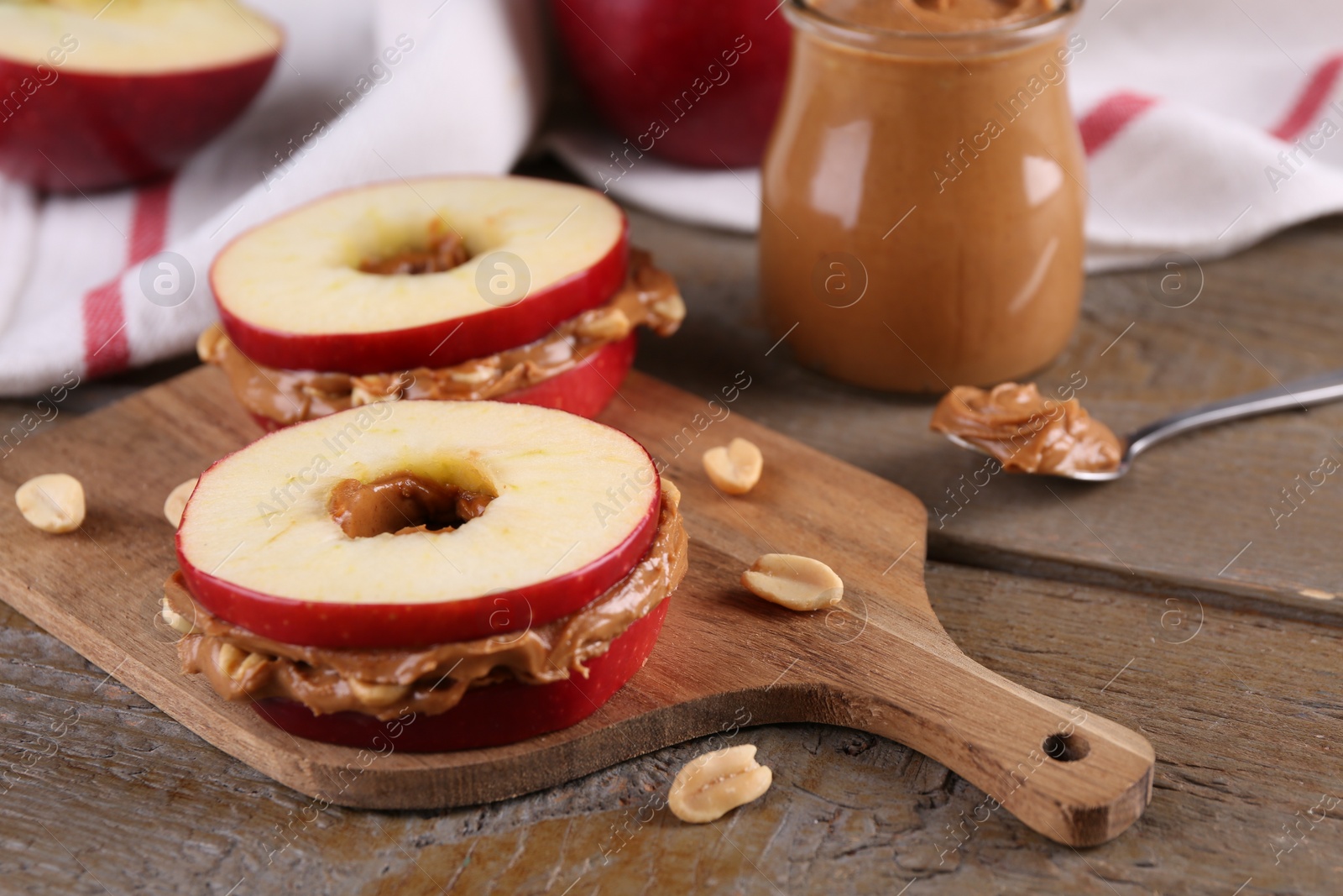 Photo of Slices of fresh apple with peanut butter and nuts on wooden table, closeup