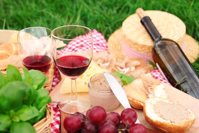 Closeup view of picnic blanket with wine and food on green grass