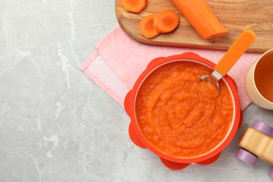 Photo of Healthy baby food. Bowl with delicious carrot puree on light grey marble table, flat lay. Space for text