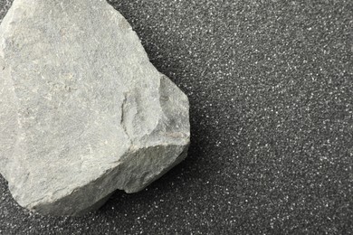 Presentation of product. Stone podium on black sand, top view. Space for text