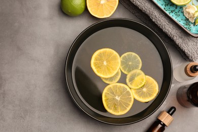 Photo of Flat lay composition with essential oil and lemons on grey table, space for text. Aromatherapy treatment