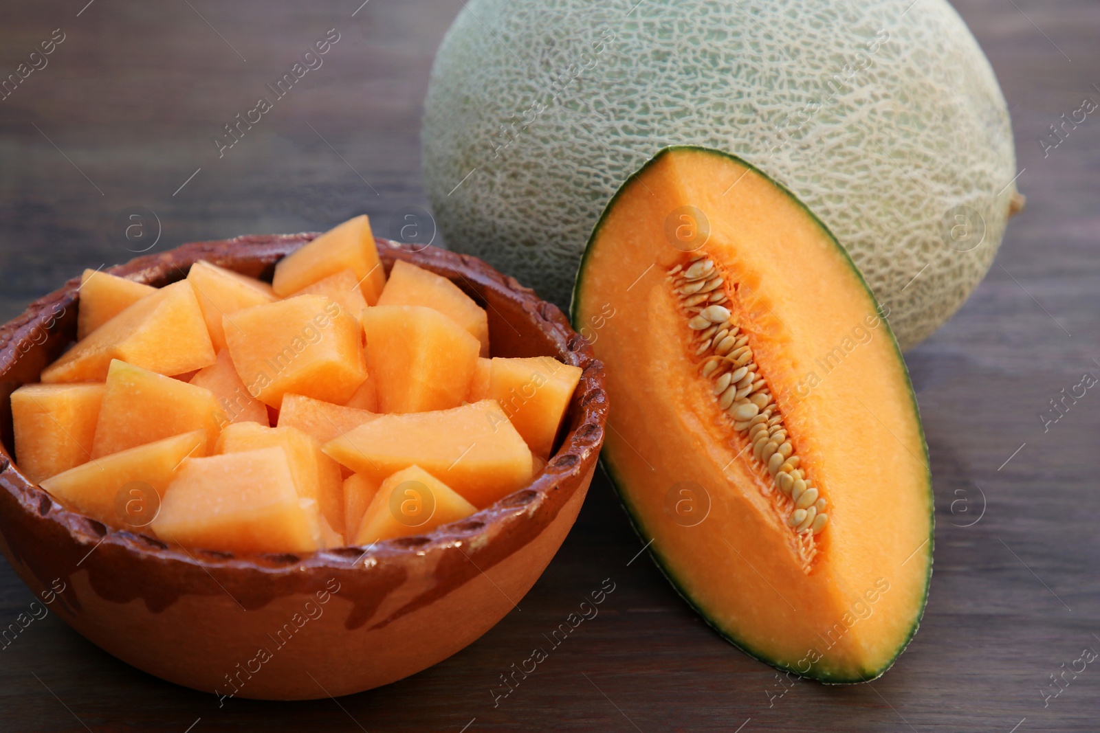 Photo of Whole and cut delicious ripe melons on wooden table, closeup