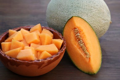 Whole and cut delicious ripe melons on wooden table, closeup