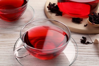 Fresh hibiscus tea and dry flower leaves on wooden table