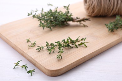 Photo of Fresh thyme and twine on white wooden table, closeup