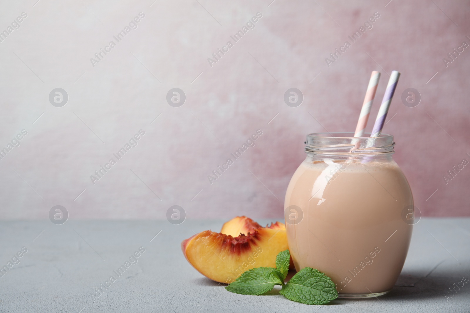 Photo of Jar of tasty milk shake and fresh peach on table. Space for text