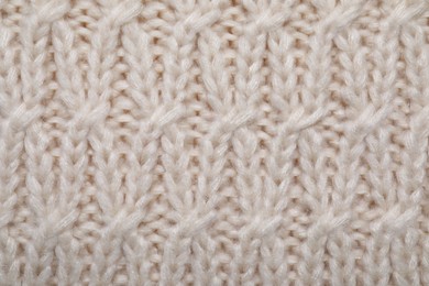 Beige knitted scarf as background, top view