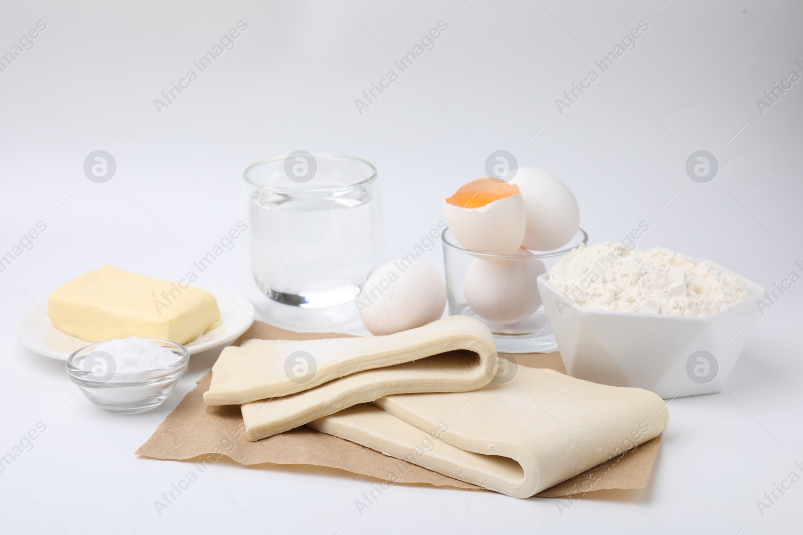 Photo of Raw puff pastry dough and ingredients isolated on white